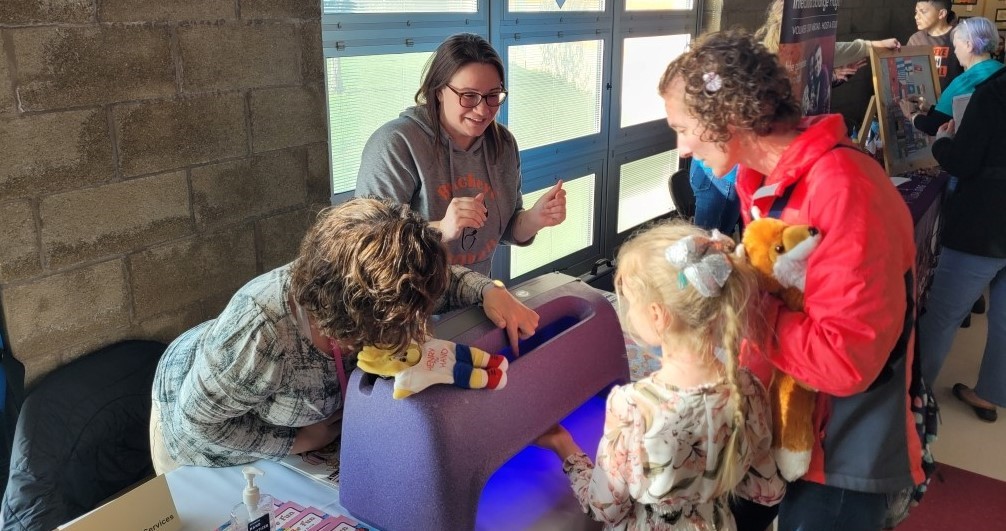Missy Cottage and Nicole High demonstrate the handwashing germ light to Buckeye students and parents.